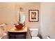 Cozy half bathroom featuring vessel sink, warm beige walls, framed art, and a round mirror at 6961 Salvia St, Arvada, CO 80007