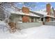 Charming home exterior with a brick chimney, cozy fence, and snow-covered yard at 3079 E Long S Cir, Centennial, CO 80122