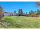 Expansive backyard with lush green grass, mature trees, wood fence, and pergola, perfect for outdoor activities at 1342 S Andes St, Aurora, CO 80017