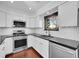 Modern kitchen featuring white cabinets, stainless steel appliances, black countertops, and subway tile backsplash at 1342 S Andes St, Aurora, CO 80017