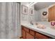 Bathroom featuring a shower with patterned curtain, wood vanity, and decorative art at 4863 Silver Spruce Ln, Evergreen, CO 80439