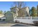 Two-story home with grey siding, white fence, and a detached two car garage at 12453 Knox Ct, Broomfield, CO 80020