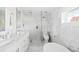Spa-like bathroom featuring marble tile, a soaking tub, a glass-enclosed shower, and dual vanities at 3884 Osceola St, Denver, CO 80212