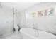 Luxurious bathroom featuring a clawfoot tub, glass shower, and marble tile at 3884 Osceola St, Denver, CO 80212