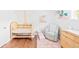 Charming Bedroom with hardwood floors, a crib, rocking chair, and a changing table at 3884 Osceola St, Denver, CO 80212