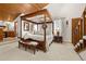 Spacious bedroom with wood ceiling, canopy bed, ensuite bathroom, and access to the staircase at 4407 Delaware Dr, Larkspur, CO 80118