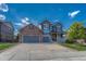 Two-story home with gray siding, brick accents, and a three-car garage at 12135 S Meander Way, Parker, CO 80138