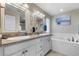 Charming bathroom featuring double granite vanities, decorative mirrors, and a soaking tub at 16197 Paris Way, Brighton, CO 80602