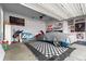 Finished garage featuring diamond pattern floor covering and car covered by tarp at 16197 Paris Way, Brighton, CO 80602