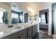 Bathroom featuring double sinks, quartz countertops, and a view into the shower and bedroom at 11830 W 52Nd Ave, Wheat Ridge, CO 80033