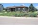 Landscaped front yard features a retaining wall with flowering plants and mature trees for added curb appeal at 7170 Windwood Way, Parker, CO 80134