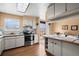 Sunlit kitchen featuring stainless steel appliances, wood floors, and a view to the backyard deck at 9720 W Kentucky Dr, Lakewood, CO 80226