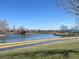 Tranquil view of a pond, green grass, walking path, and blue-roofed gazebos in a park setting at 9720 W Kentucky Dr, Lakewood, CO 80226