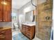 Bathroom with beautiful wooden cabinetry, shower with tile surround, modern fixtures, and plenty of natural light at 13080 County Road 19, Platteville, CO 80651