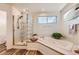 Bright bathroom with glass shower, large tub, wood look floors, and a view to the outside at 270 Terra Vista St, Brighton, CO 80601