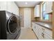 Bright laundry room with white cabinetry, modern appliances, and a window at 775 Woodgate Dr, Littleton, CO 80126