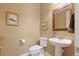 Cozy powder room with pedestal sink, decorative mirror, and neutral wall paint at 775 Woodgate Dr, Littleton, CO 80126