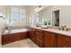 Bright bathroom features a soaking tub, dual vanity, and large mirror at 9581 Firenze Way, Highlands Ranch, CO 80126