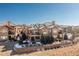 Back exterior of the home featuring large windows, balconies, stone retaining wall and mature evergreens at 9581 Firenze Way, Highlands Ranch, CO 80126