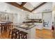 Open kitchen with island, breakfast bar, hardwood floors, white cabinets, and access to dining area at 4967 E Lake Ave, Centennial, CO 80121