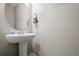 A small powder room includes a pedestal sink, round mirror, and modern accessories at 14075 Scarlet Sage St, Parker, CO 80134