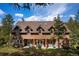 Charming two-story home featuring a welcoming front porch with hanging flower baskets and a beautiful natural setting at 4978 Camel Heights Rd, Evergreen, CO 80439