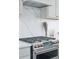 Stainless steel gas range and hood in the bright kitchen with quartz countertops and backsplash at 4978 Camel Heights Rd, Evergreen, CO 80439