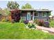 Charming gray home featuring manicured lawn, colorful flowerbeds and brick pathway at 6223 Gray St, Arvada, CO 80003