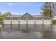 Row of six private garages featuring white doors and stone accents, perfect for secure parking and extra storage at 13275 Holly St # E, Thornton, CO 80241