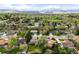 An aerial view of a neighborhood reveals homes nestled among trees and green spaces with mountain views in the distance at 3322 Simms St, Wheat Ridge, CO 80033