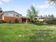 Charming home with a well-maintained lawn, mature trees, and a classic brick facade, radiating curb appeal at 3322 Simms St, Wheat Ridge, CO 80033