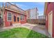 Backyard view featuring a concrete patio, small lawn area, and red-painted siding and a small balcony at 1356 N Marion St, Denver, CO 80218