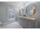 Bright bathroom with a double vanity, marble countertop, oval mirrors, and stylish black and white patterned floor at 1356 N Marion St, Denver, CO 80218