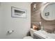 Stylish half bathroom showcasing a modern sink, round mirror, wood wall accent and tasteful decor at 12935 W 64Th Dr # D, Arvada, CO 80004