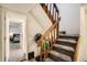 Staircase with carpeted steps and a wooden railing, leading to upper level, featuring a glimpse of a bedroom at 12935 W 64Th Dr # D, Arvada, CO 80004