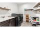 Clean laundry room with a washer, dryer, sink, cabinets, and floating shelves at 303 Rogers Ct, Castle Rock, CO 80104