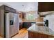 Well-lit kitchen with stainless steel appliances, granite countertops, and dark wood cabinets at 6769 S Foresthill St, Littleton, CO 80120