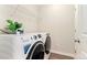 Bright laundry room with modern, white, front-loading washer and dryer units and wire rack at 7602 S Yakima Ct, Aurora, CO 80016