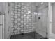 Sleek glass enclosed shower with geometric patterned accent wall, black hardware and dark tile floor at 4570 Irving St, Denver, CO 80211