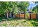 Landscaped front yard featuring a gray stone facade, mature trees, modern wood fence, and well-maintained lawn at 4570 Irving St, Denver, CO 80211