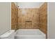 Bathroom featuring a tile wall, niche in the wall, shower head, and white tub at 19721 E Vassar Ave, Aurora, CO 80013