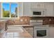 Bright kitchen featuring white appliances, tile backsplash and view from window at 19721 E Vassar Ave, Aurora, CO 80013