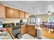 Traditional kitchen features wooden cabinets, black countertops, and a dining area with hardwood floors at 7751 Niagara St, Commerce City, CO 80022