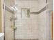 Shower with mosaic accent and a hand shower with shower caddy and glass shower door at 7751 Niagara St, Commerce City, CO 80022