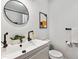 Modern bathroom featuring a black faucet, round mirror, and stylish decor at 2427 S Eldridge Ct, Lakewood, CO 80228