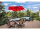 Relax on this inviting outdoor deck featuring comfortable seating and a charming red umbrella for shade at 1590 Longview Cir, Monument, CO 80132