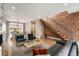 A spacious living room featuring exposed brick wall, modern staircase, hardwood floors and stylish furnishings at 3126 Perry St, Denver, CO 80212