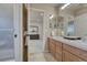 Bathroom featuring double sinks, wooden cabinets, and an open view to bedroom at 580 Eagle Nest Ct, Golden, CO 80401