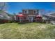 Spacious backyard featuring a lush lawn, a wooden deck, and a red umbrella for outdoor relaxation at 18655 E Garden Pl, Aurora, CO 80015