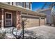 Well-kept home featuring a three-car garage, brick accents, and a cozy, covered porch entrance at 18655 E Garden Pl, Aurora, CO 80015